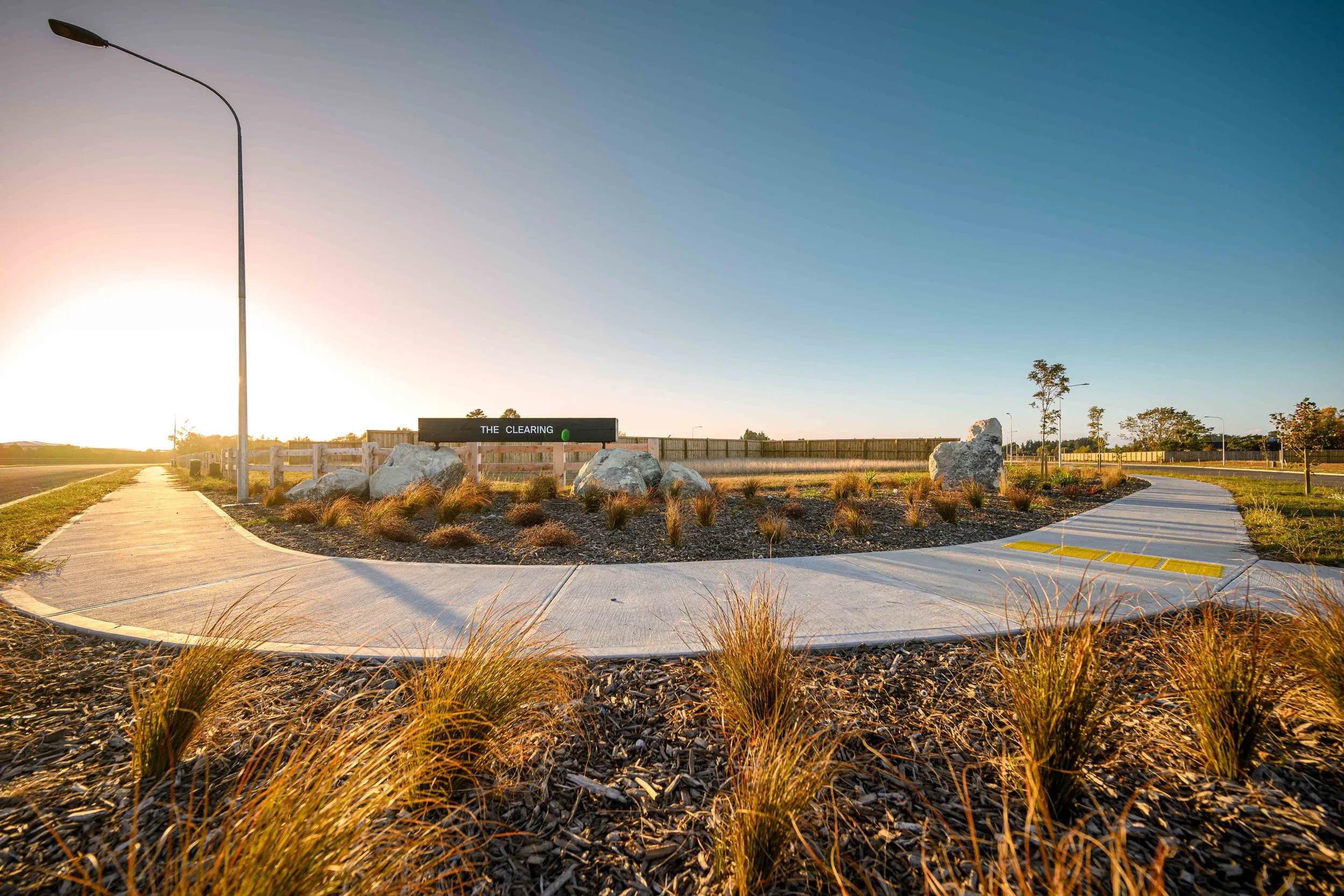 Sunlit Amberley with modern pathways and native planting, a peaceful residential hub in New Zealand.