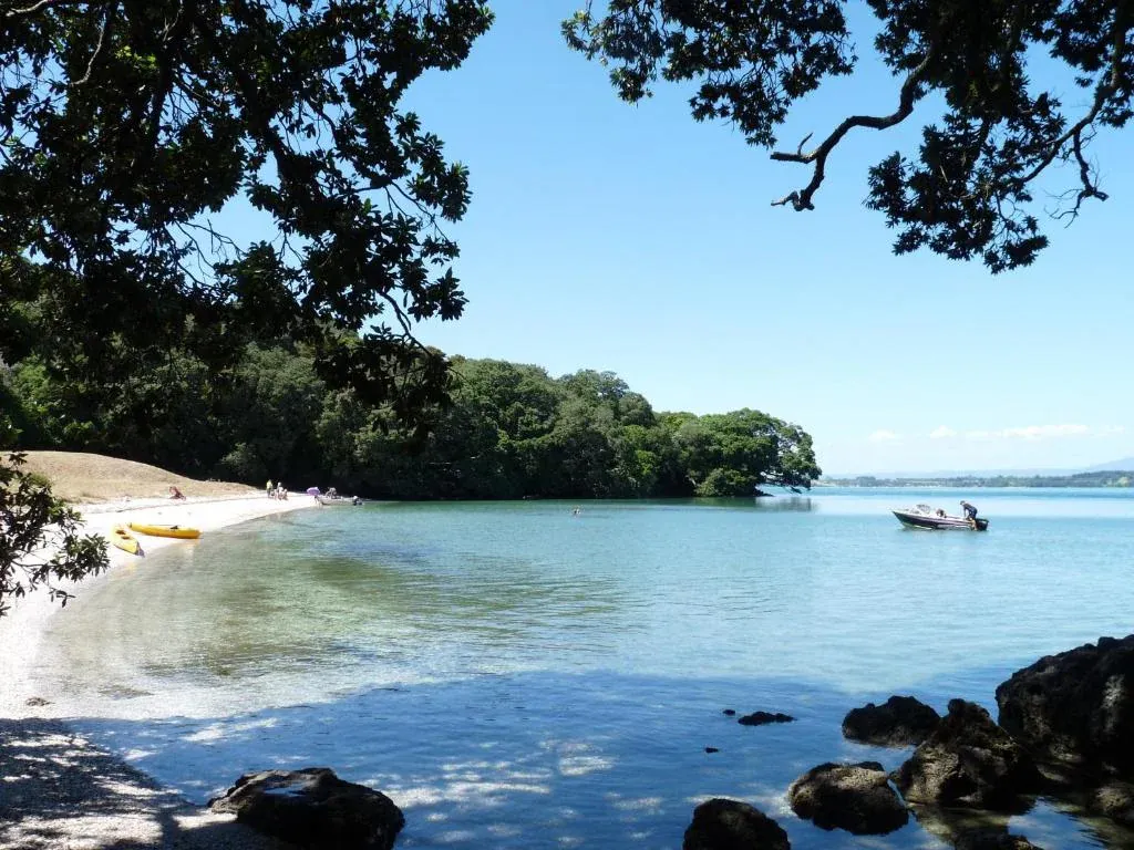 Idyllic Athenree beach with calm waters, ideal for boating, kayaking, and family picnics in New Zealand.