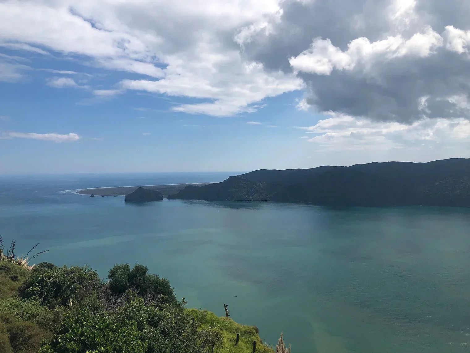 Serene Awhitu Peninsula coastal view with clear waters and lush greenery in New Zealand.