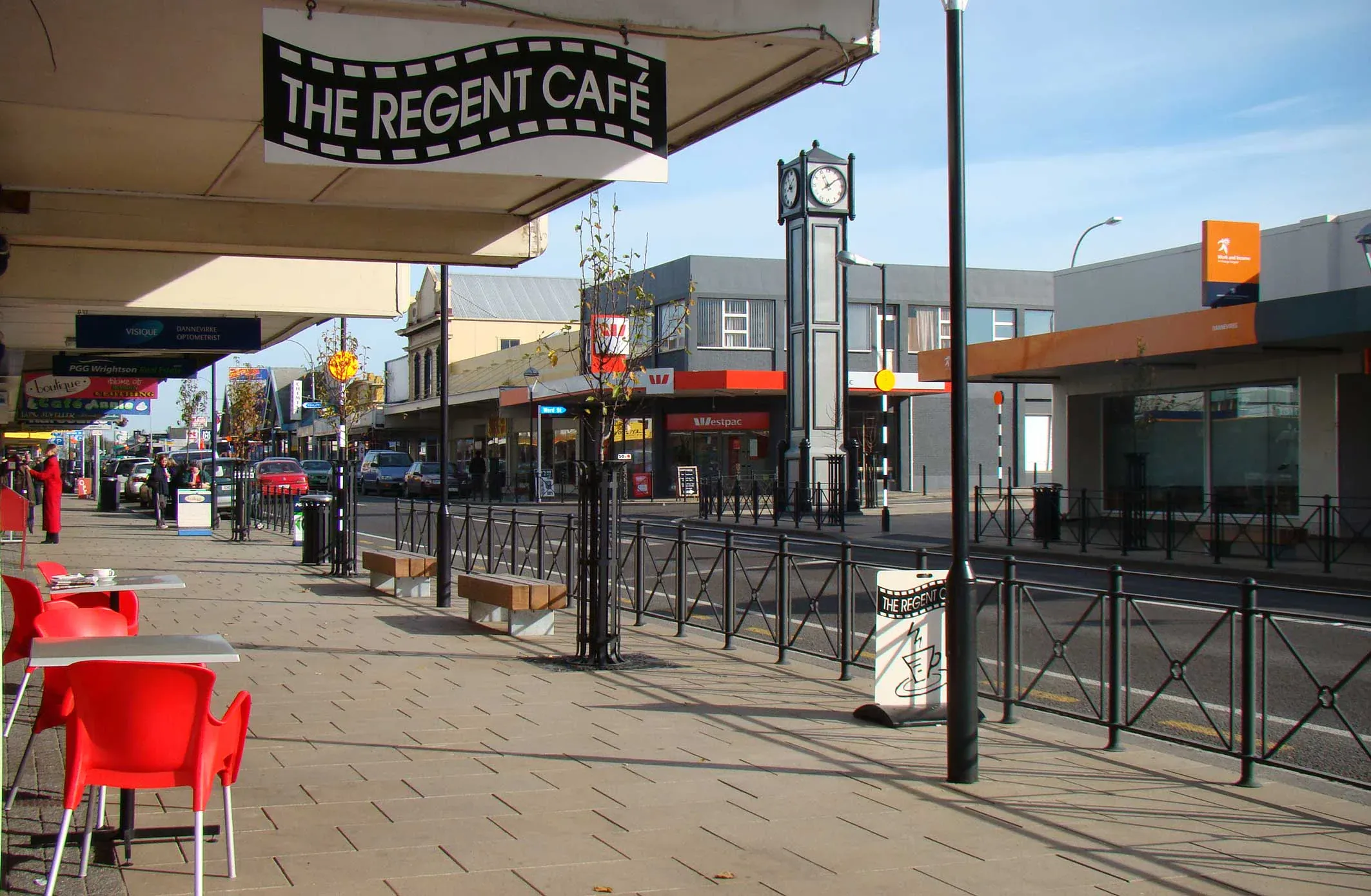 Dannevirke main street with café seating and clock tower, showcasing local retail and dining options.