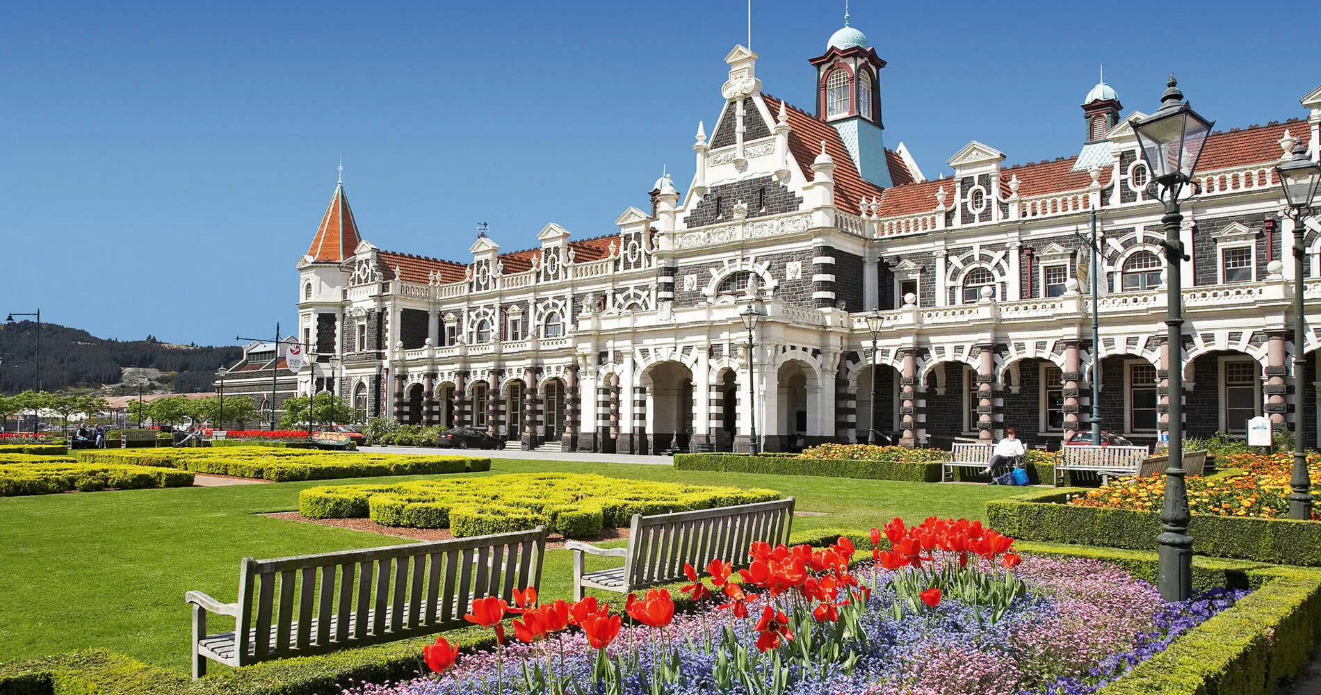 Dunedin Railway Station with gardens, an iconic landmark promoting tourism and local businesses.