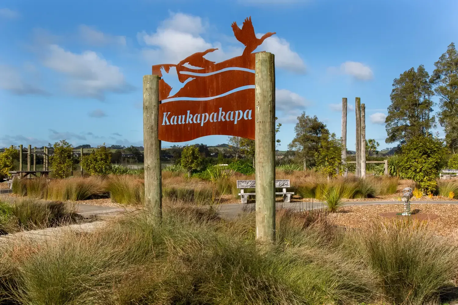 Kaukapakapa village sign amidst scenic greenery, ideal for local businesses and services.