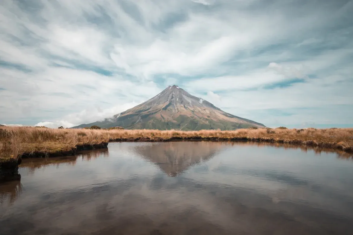 Secluded beach with lush hills and tranquil water in Korito, Taranaki, New Zealand.