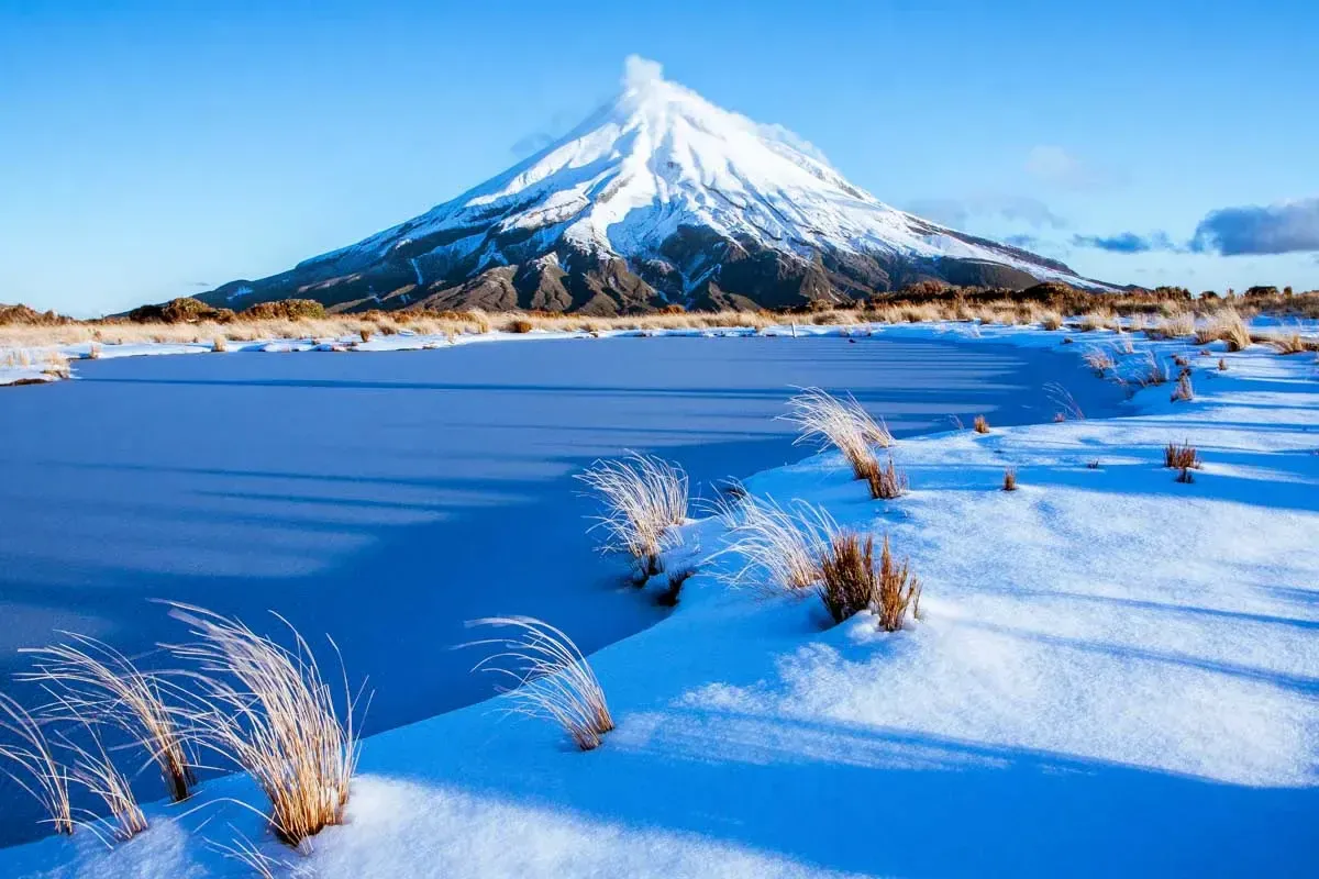 Snow-capped Mount Taranaki and frosted landscape in Lepperton, New Zealand.