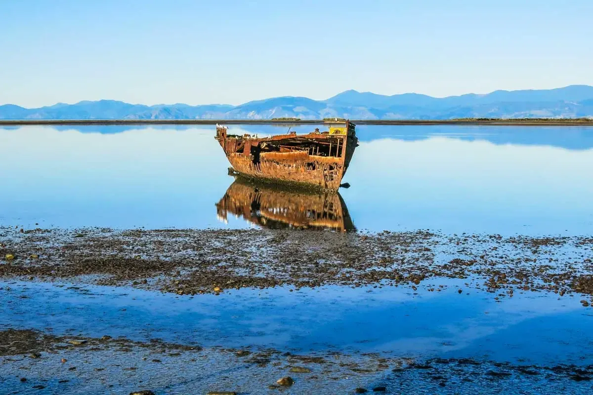 Rusted shipwreck in Motueka inlet, emphasizing maritime history and coastal tourism.