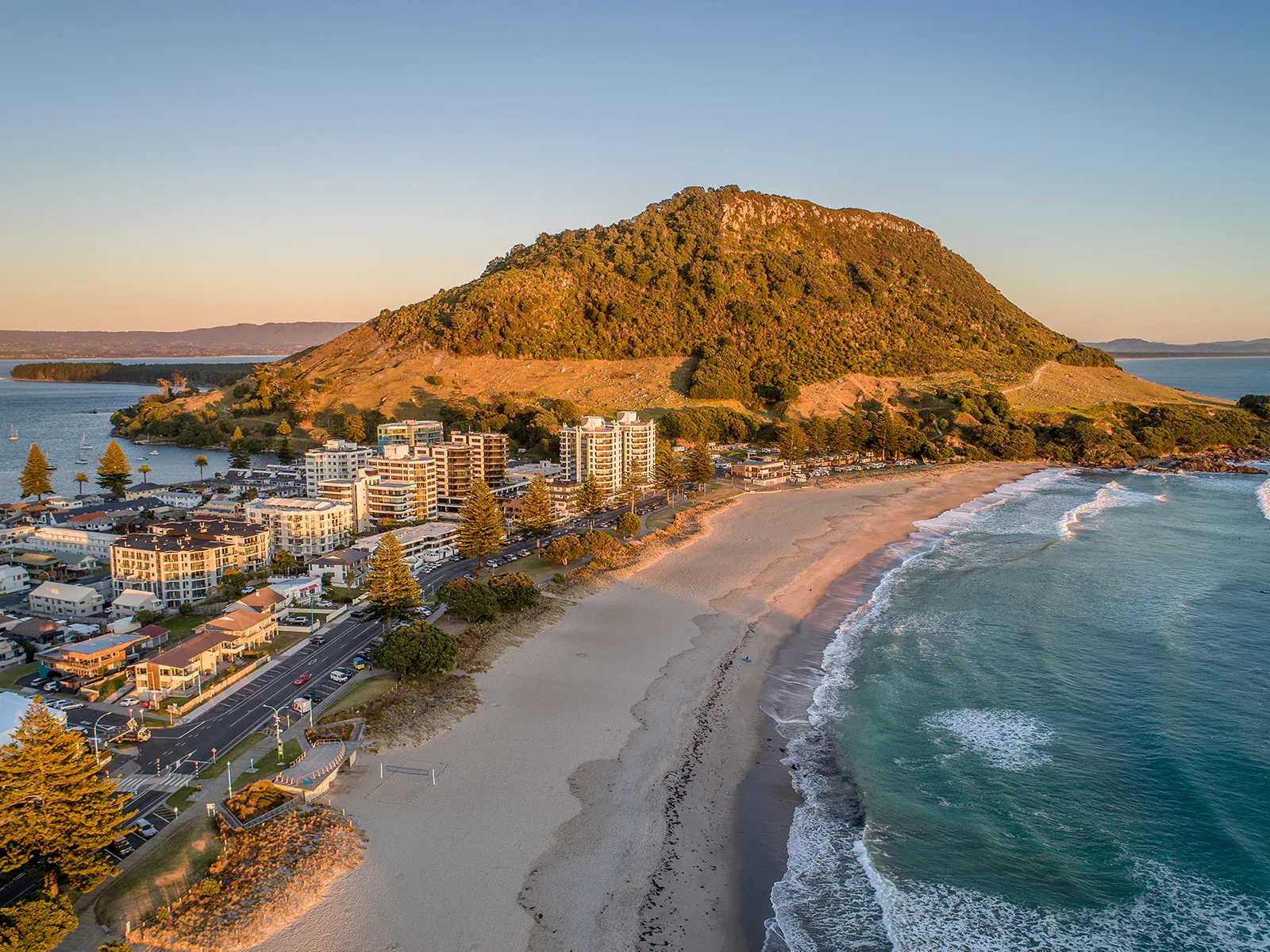 Mount Maunganui beach and iconic hill with vibrant urban development, perfect for tourism and retail.