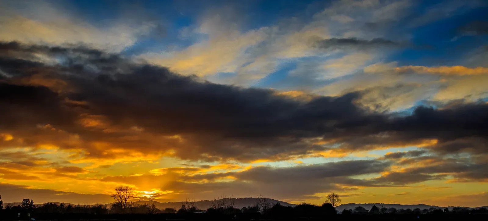 Golden hues in the evening sky over rolling hills, Netherton, New Zealand.