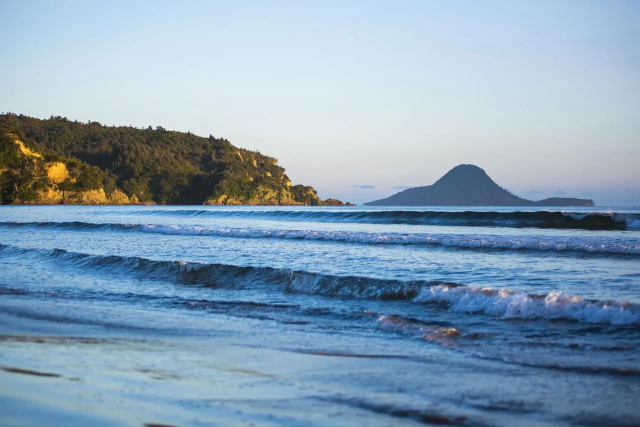 Ohope Beach with gentle waves and Whale Island in the distance, highlighting Whakatane's coastal charm.